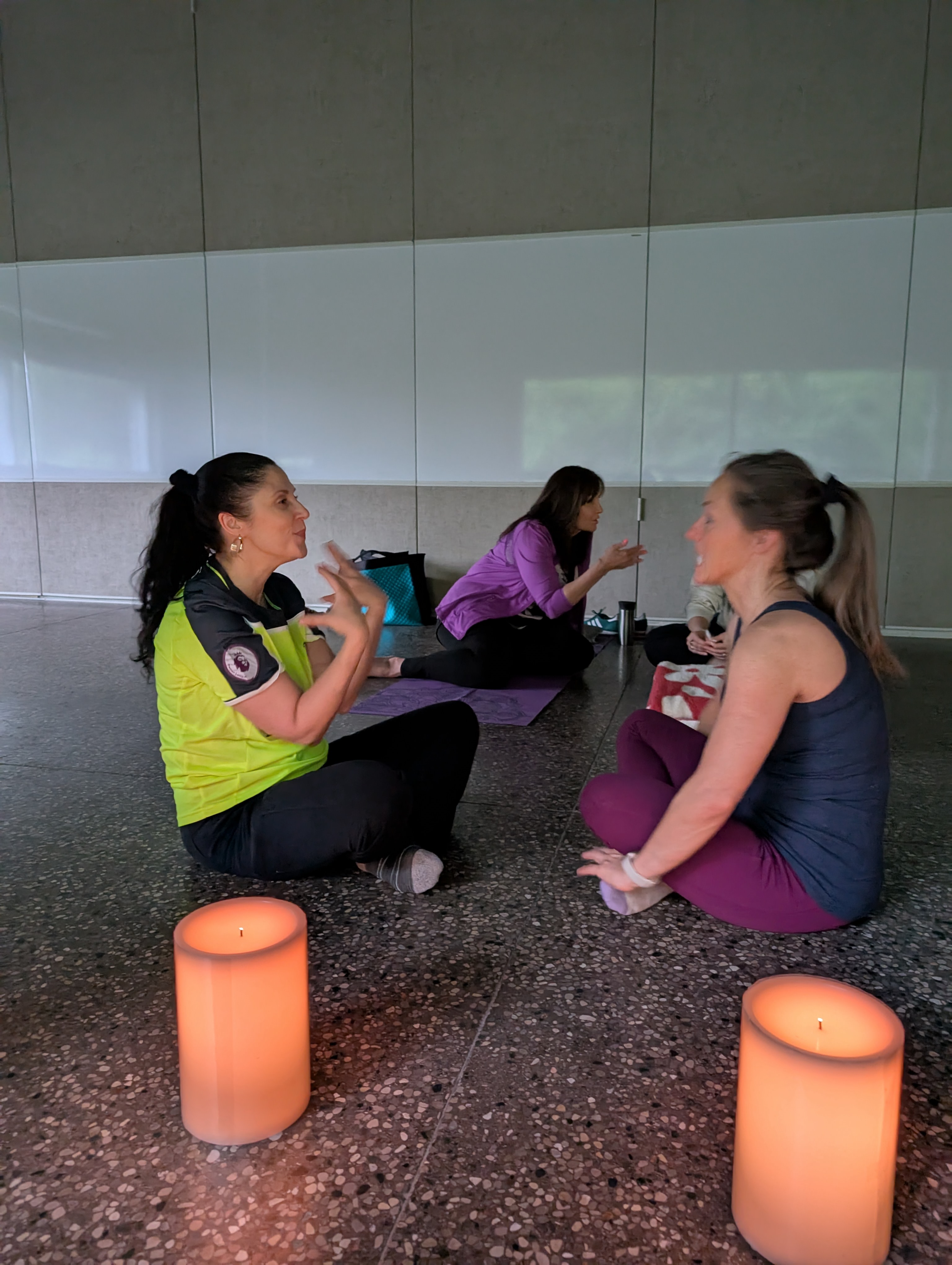 Joanna talking with two members of the community, sitting in a circle by candlelight