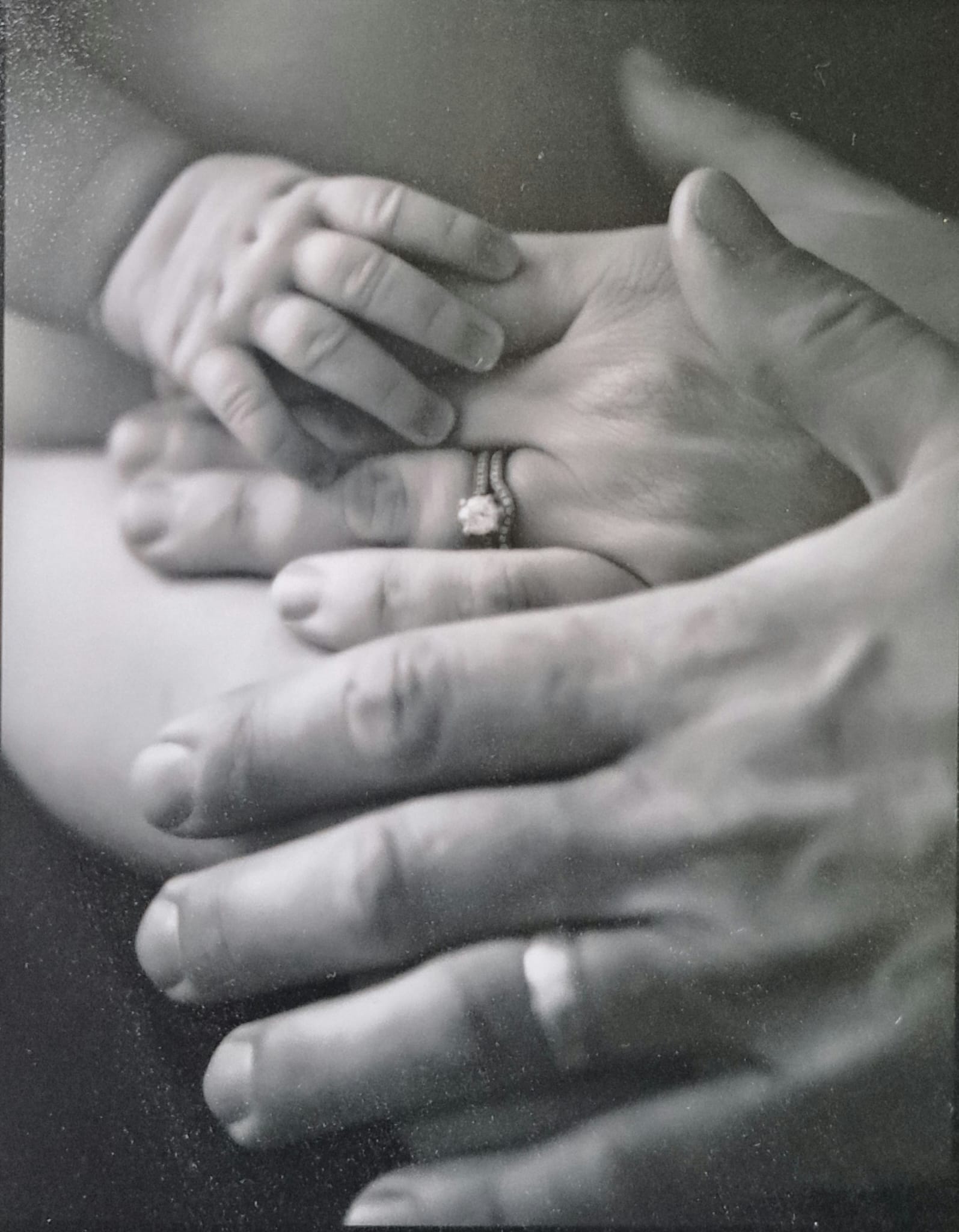 A couple's hands and their newborn's hand together